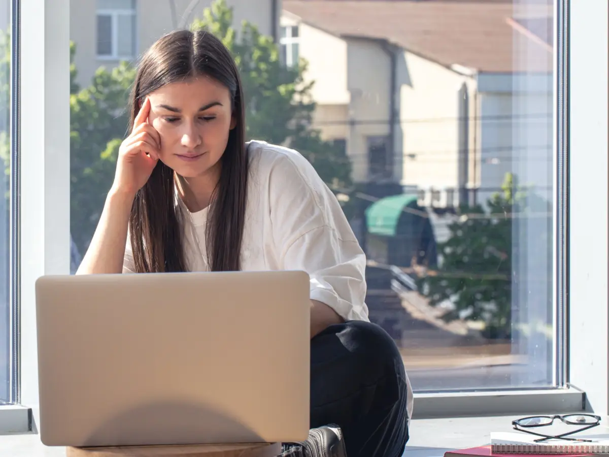Müde Frau am Laptop vor dem Fenster